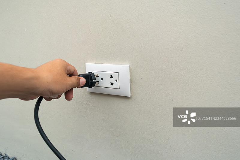 特写镜头：一只男人的手将插头插入插座图片素材