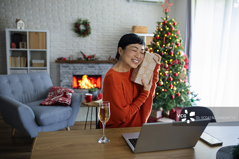 一位女士在与家人的视频通话中展示她的圣诞礼物图片素材