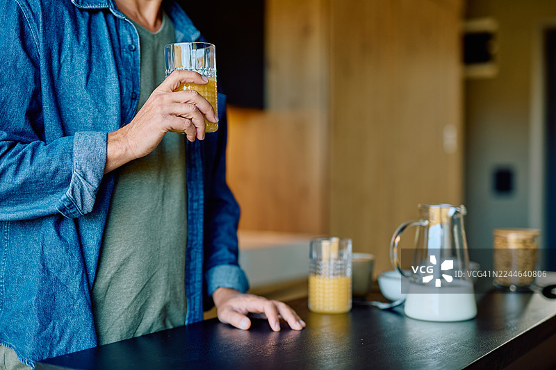 男人在厨房享用早餐，喝着橙汁图片素材