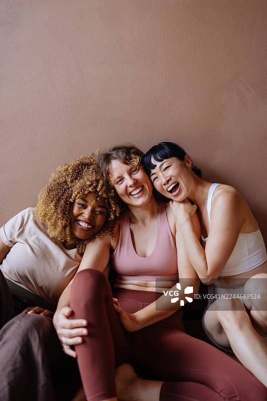 三个朋友在粉色墙边进行休闲锻炼时开怀大笑图片素材