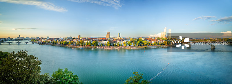 日落时分，瑞士巴塞尔市巴塞尔地区和莱茵河码头的长曝光全景图，展示了两座著名的拱桥、21世纪的罗氏双塔摩天大楼以及河畔长廊，位于巴塞尔城市州。图片素材