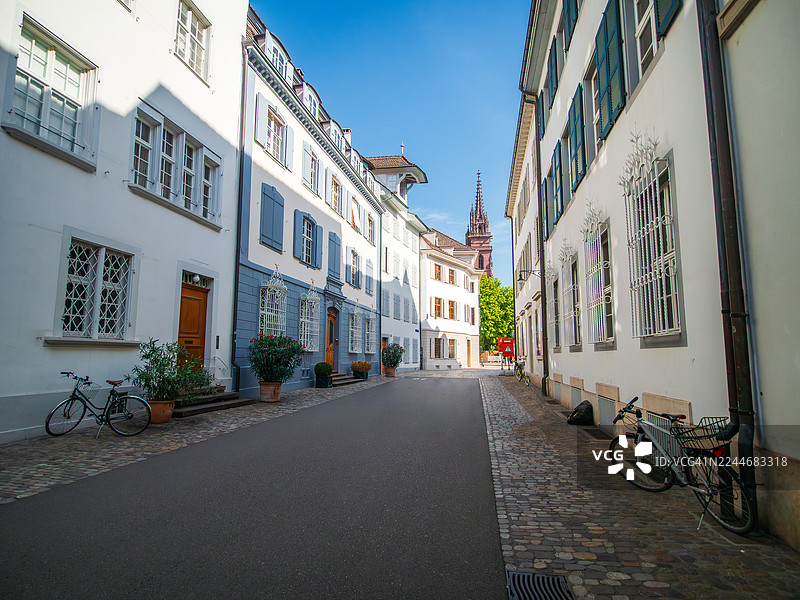 从广角视角拍摄的巴塞尔市中心和老城区空旷的步行街，街道上有自行车、盆栽植物、色彩缤纷的百叶窗房屋，并能远眺巴塞尔大教堂（或名主教座堂）的尖塔，位于瑞士巴塞尔城市州。图片素材