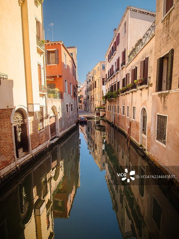 意大利威尼斯圣保罗区里奥德弗拉里运河平静水面上的住宅楼和公寓倒影,有水上入口,船只停靠在码头,这里是联合国教科文组织世界遗产地——威尼托——意大利。图片素材