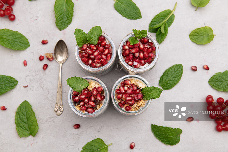 俯视视角，罐装奇亚籽布丁，配有石榴和薄荷，置于灰色背景上图片素材