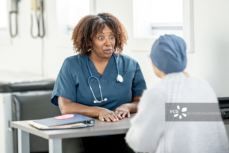 身穿手术服的非裔女护士在诊所办公室里，富有同情心地与患者进行咨询。图片素材