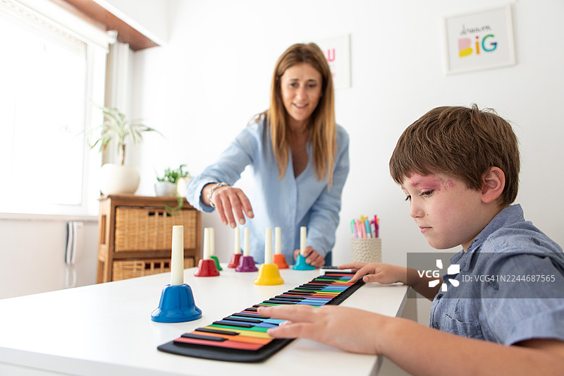 患有斯特奇-韦伯综合征的男孩在音乐治疗课上弹奏键盘图片素材