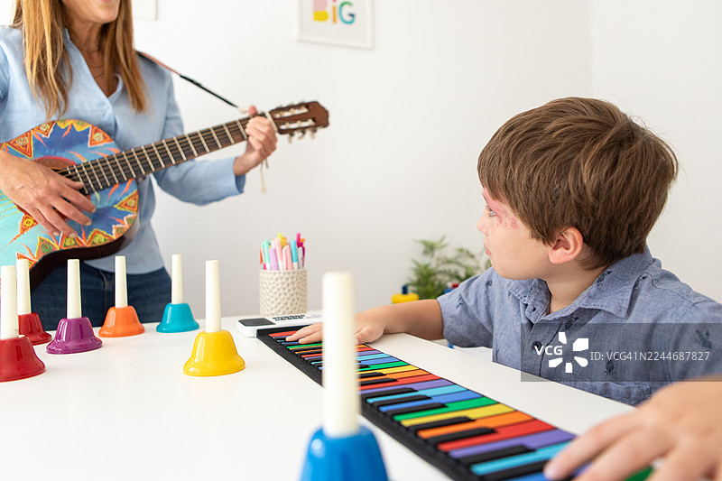 患有斯特奇-韦伯综合征的男孩在音乐治疗课上弹奏键盘图片素材