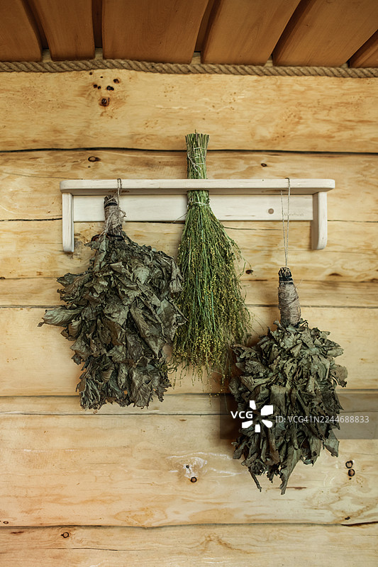 汗蒸房木墙上悬挂着由干橡树叶制成的天然搅拌器。图片素材
