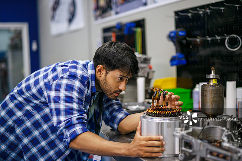 一名机械师正在电动汽车维修车间工作。图片素材