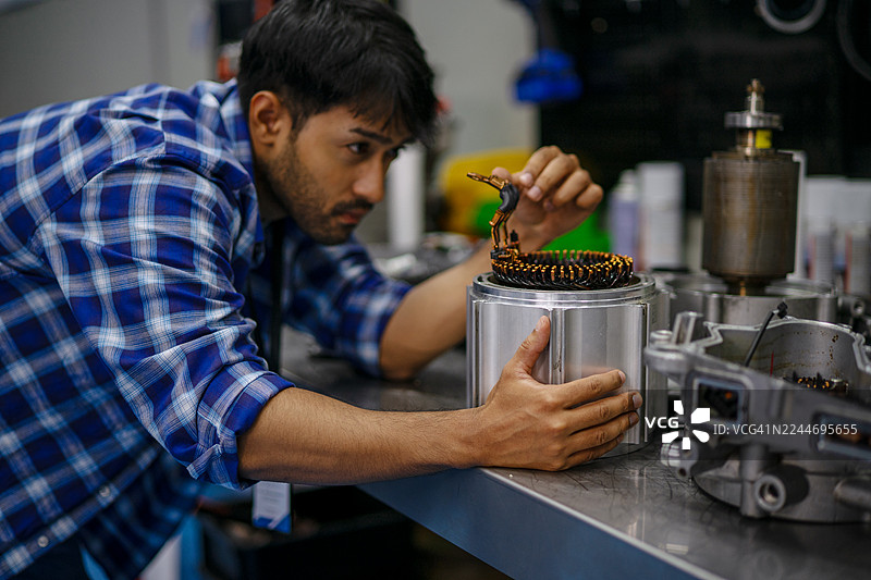 机械师正在电动汽车维修车间工作。图片素材