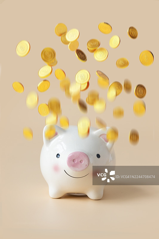 概念性的财务自由概念静物，金币飞在一只存钱罐上方。图片素材
