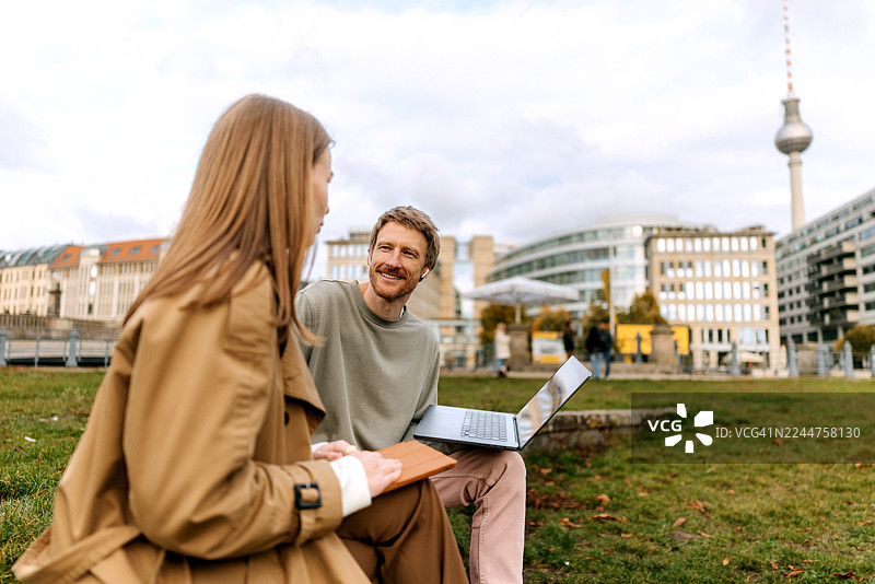 朋友们在柏林老博物馆附近放松，同时使用笔记本电脑和平板电脑图片素材