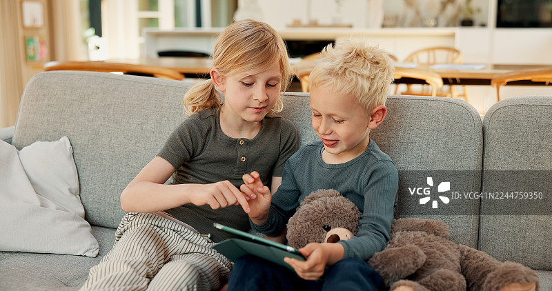 家人、孩子在沙发上玩平板电脑，进行在线游戏、解决问题和增进感情。兄弟姐妹、孩子们在家放松，玩数字应用程序，进行单词搜索游戏、享受周末休息或进行开发。图片素材