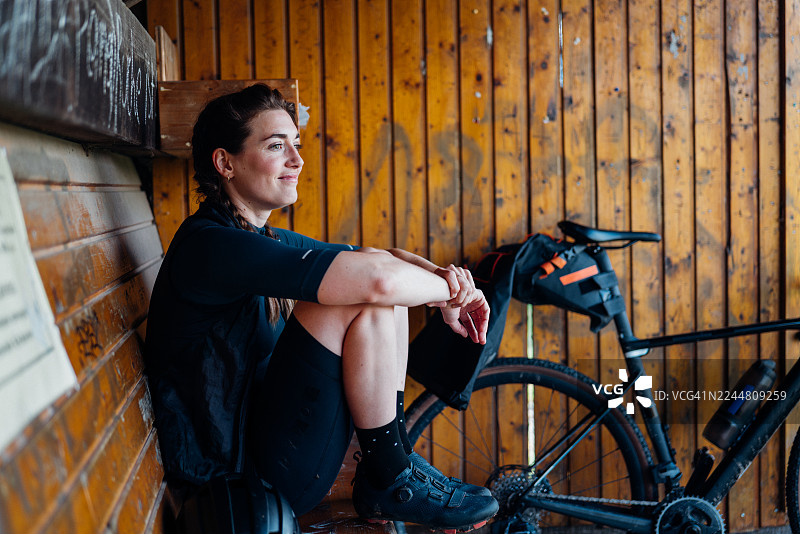 骑行后，一位运动女性在木制自行车棚内享受宁静的反思时刻图片素材