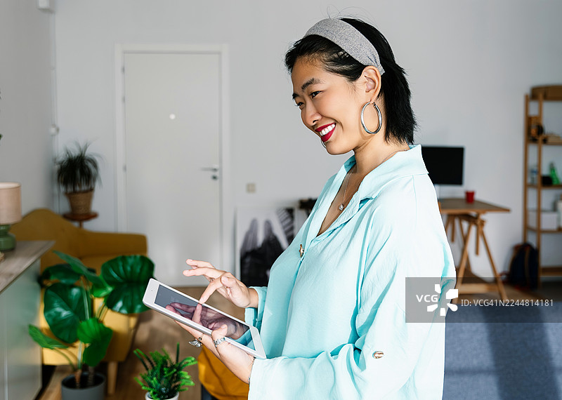 年轻亚洲女性使用带有智能家居应用程序的平板电脑图片素材