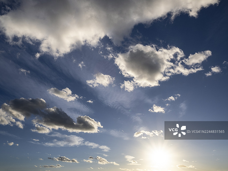日落时分多云的天空，在地平线上有阳光穿透。图片素材
