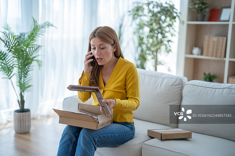 Woman calling customer service after receiving damaged photo frame图片素材