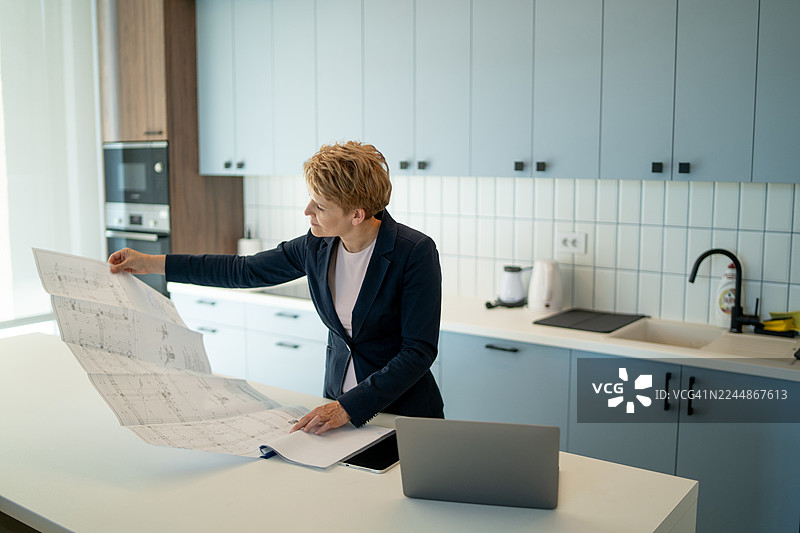 建筑师在现代厨房里阅读蓝图图片素材