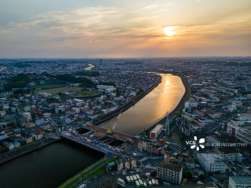 横滨市鹤见区和川崎市川崎区、幸区之间正在进行主要桥梁更换工程。日落倒映在河面上，这是一座横跨河流的桥梁。无人机拍摄的鹤见川航拍画面。图片素材
