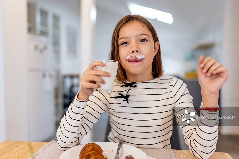 早餐桌前，一个留着牛奶胡子的有趣女孩图片素材