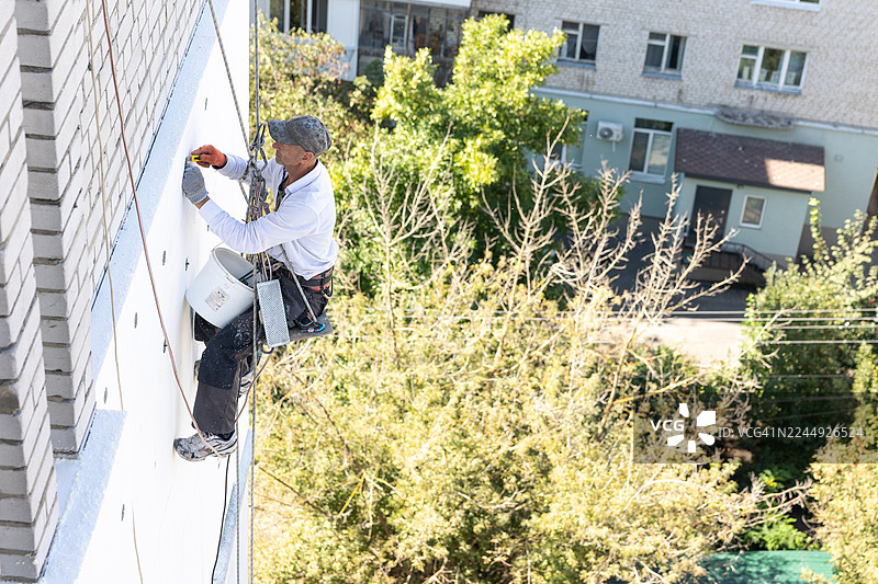 建筑工人正在用锚栓固定聚苯乙烯板，用于外墙保温。图片素材