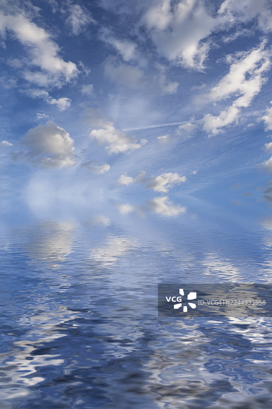 地平线上清晰的天空中，有几朵小而柔软的云彩倒映在水中。图片素材