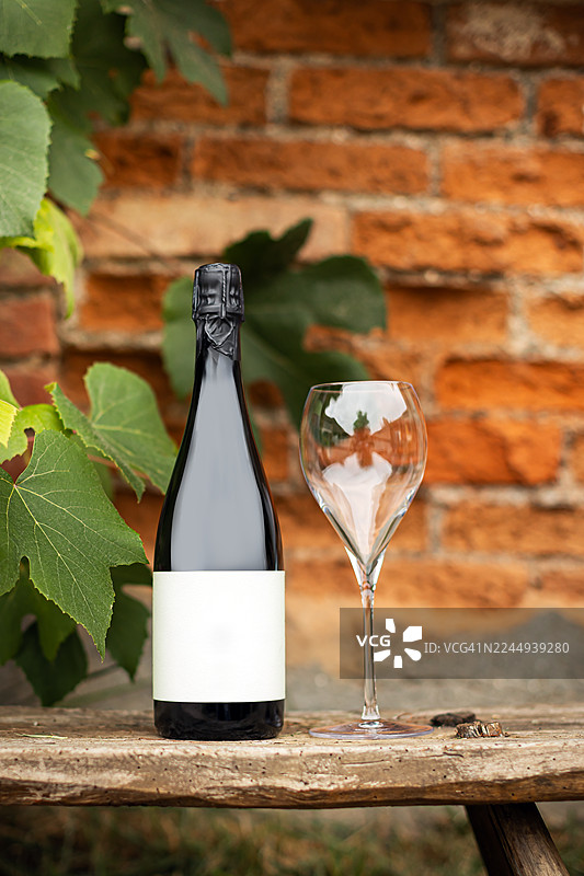 老旧木凳上放着酒瓶和酒杯，背景是砖墙图片素材