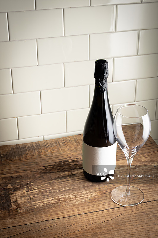 木桌上的酒瓶和酒杯，瓷砖墙背景图片素材