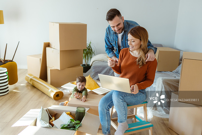 夫妻和孩子在新公寓里使用信用卡进行在线购物图片素材