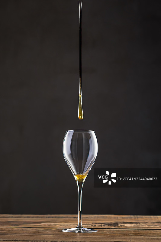 蜂蜜滴落在木桌上的酒杯上图片素材