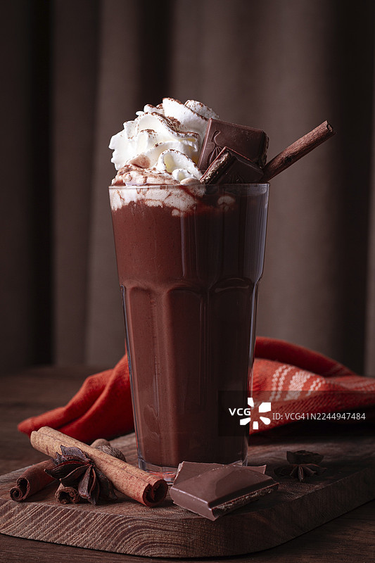 热巧克力饮品，上面饰有鲜奶油、巧克力碎和肉桂棒图片素材