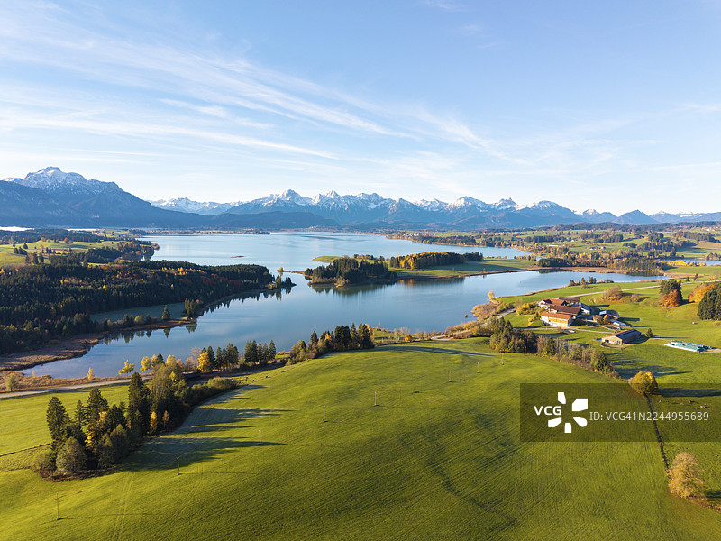 碧空下,绿色的山丘和山峦环绕着伊拉斯贝格湖(Illasbergsee)和福尔格湖(Forggensee),位于德国巴伐利亚州施瓦本行政区菲森附近。图片素材