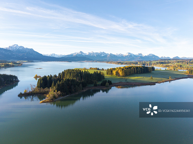 宁静的湖泊和秋季森林,背景为阿尔卑斯山全景,位于德国巴伐利亚州施瓦本地区奥斯特阿尔高县罗斯豪普滕附近的伊拉森贝格湖和福尔格湖。图片素材