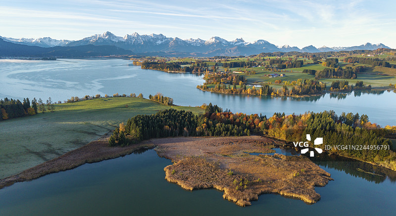 秋日湖景，湖泊周围环绕着绿色景观和山峦，位于德国巴伐利亚州施瓦本地区奥斯特戈伊区福尔格根湖附近的伊拉斯贝格湖图片素材