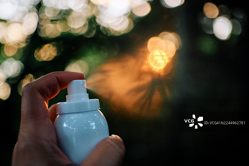 特写镜头下，一只手在自然和森林的背景下喷洒气雾剂。图片素材