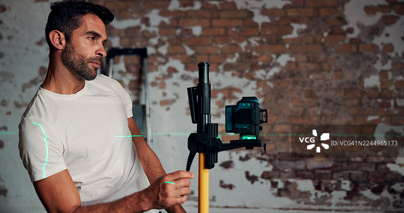 建筑工人使用激光水平仪测量墙面，用于场地规划、测量或翻新项目。土木工程师、技术人员或设备用于对齐、地基找平和精确测量，预留空间。图片素材