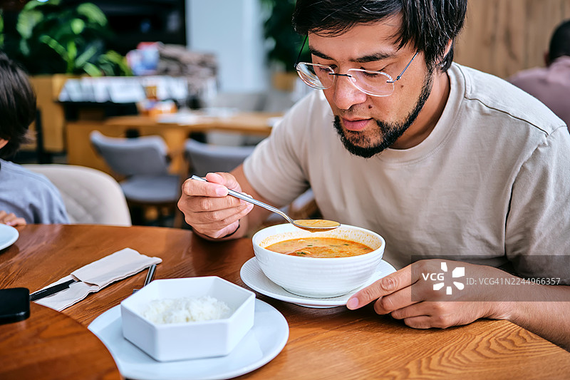 男人在餐厅享用亚洲汤饭图片素材