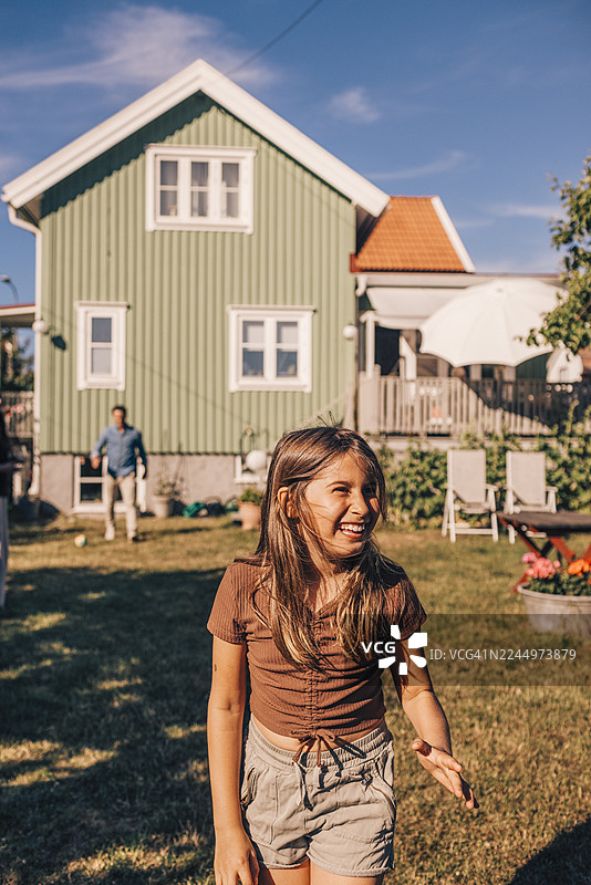 阳光明媚的日子里，一个快乐的女孩在后院欣赏风景，目光望向远方图片素材