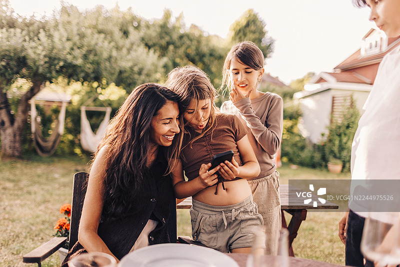 女儿在后院向妈妈展示智能手机图片素材