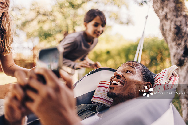 女儿们和爸爸一起躺在吊床上玩耍图片素材