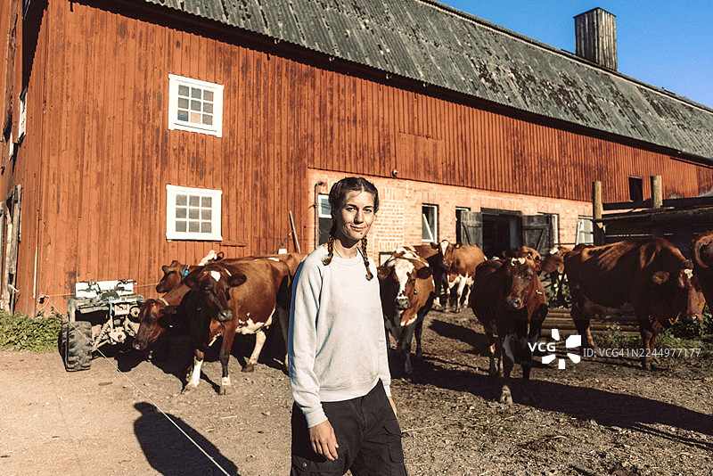 一位面带微笑的女农民，牛正走出谷仓的肖像图片素材