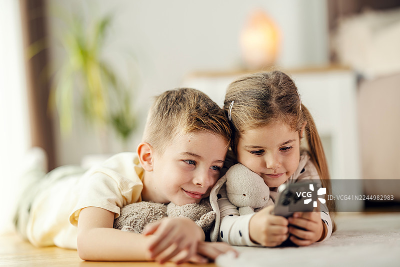孩子们在家分享智能手机进行在线娱乐图片素材