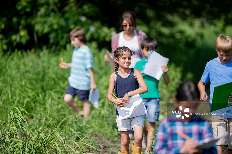 一群孩子在户外进行科学活动，手持纸张和铅笔图片素材