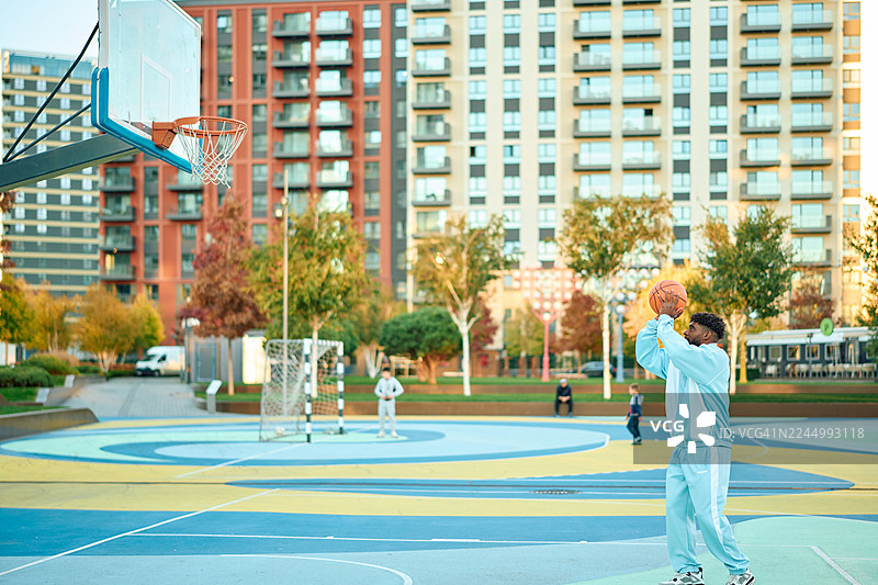 年轻男子在城市篮球场上投篮图片素材