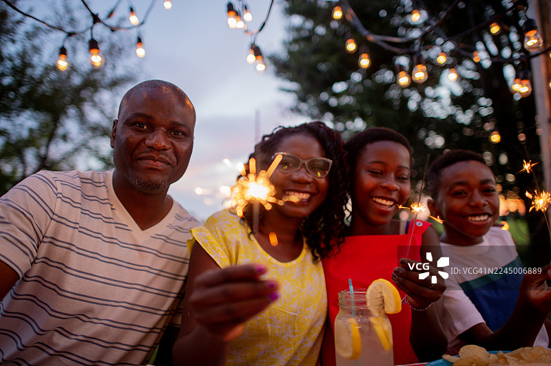 欢乐的黑人家庭和朋友在户外庆祝活动中，手持仙女棒，饮用柠檬饮品图片素材