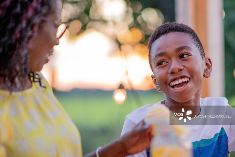 欢乐的黑人家庭，男孩在户外烧烤晚宴上与女士一同欢笑图片素材
