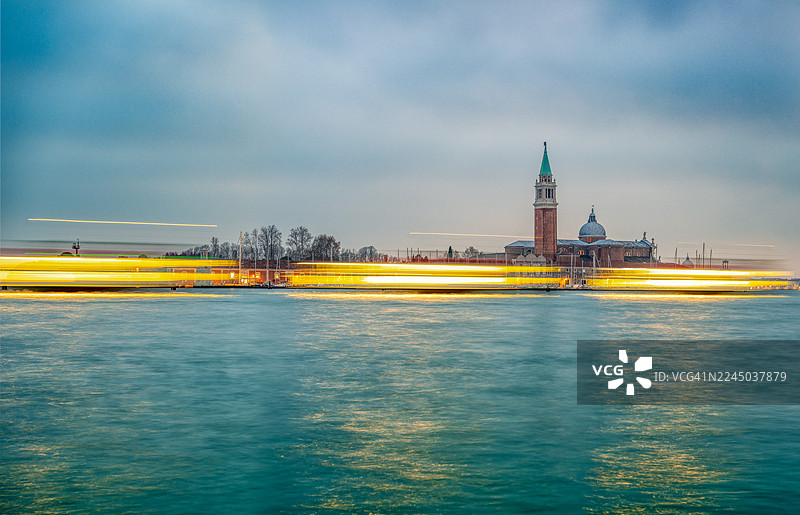 日落时分威尼斯潟湖船只灯光轨迹的长曝光，背景为圣乔治马乔雷岛，意大利威尼斯图片素材