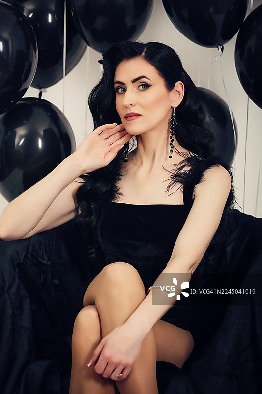 身着黑裙的优雅年轻女子手持气球，庆祝特别的时刻图片素材