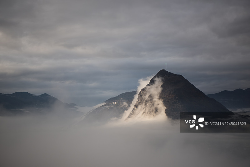瑞士卢加诺圣萨尔瓦托雷，山峰被薄雾和云层笼罩，天空阴沉，戏剧性的山景图片素材