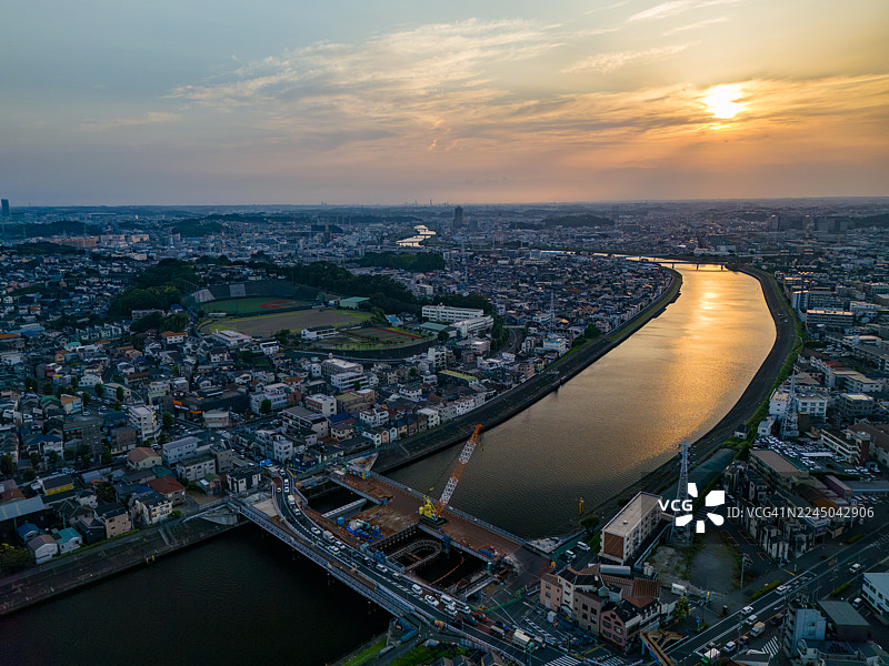 横滨市鹤见区正在进行主要桥梁更换工程。夕阳倒映在河面上，一座桥横跨河流。无人机航拍鹤见川，往西是横滨市鹤见区，往东是川崎市川崎区和幸区。图片素材